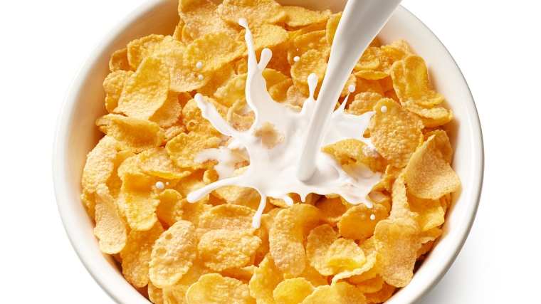 Pouring milk in a bowl of cereal.